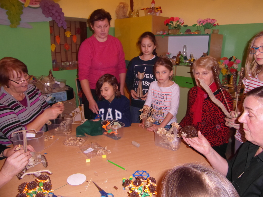 Zdjęcie przedstawia osoby dorosłe i dzieci podczas wykonywania prac plastycznych