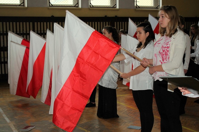 Przedstawienie: dziewczęta w białych koszulkach poplamionych krwią z flagami Polski