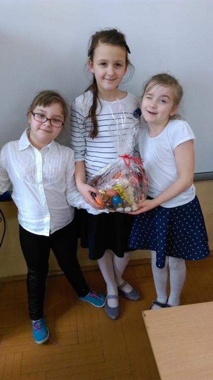 Trzy dziewczynki prezentują paczkę ze słodyczami 
